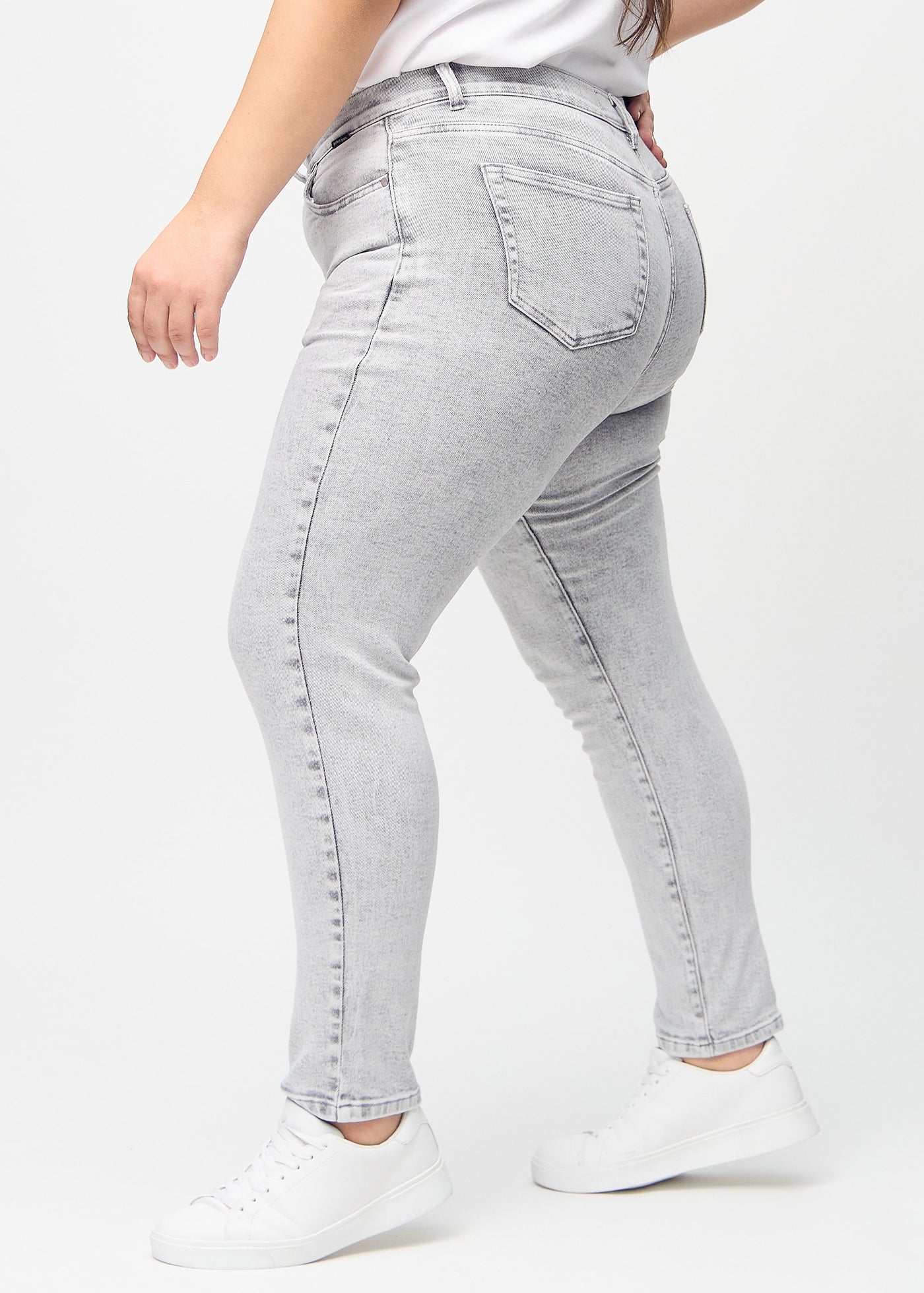 Lysegrå denim slim jeans set fra siden på en plus-size model.