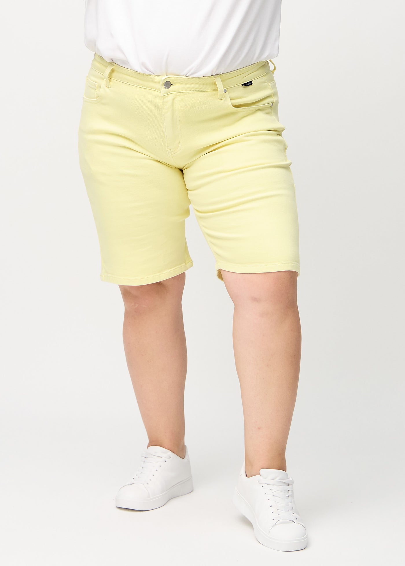 Lysegule regular middle shorts, modelnavn Lemonades, som går lige ned langs benet og slutter lige over knæet på en plus-size model, set forfra.
