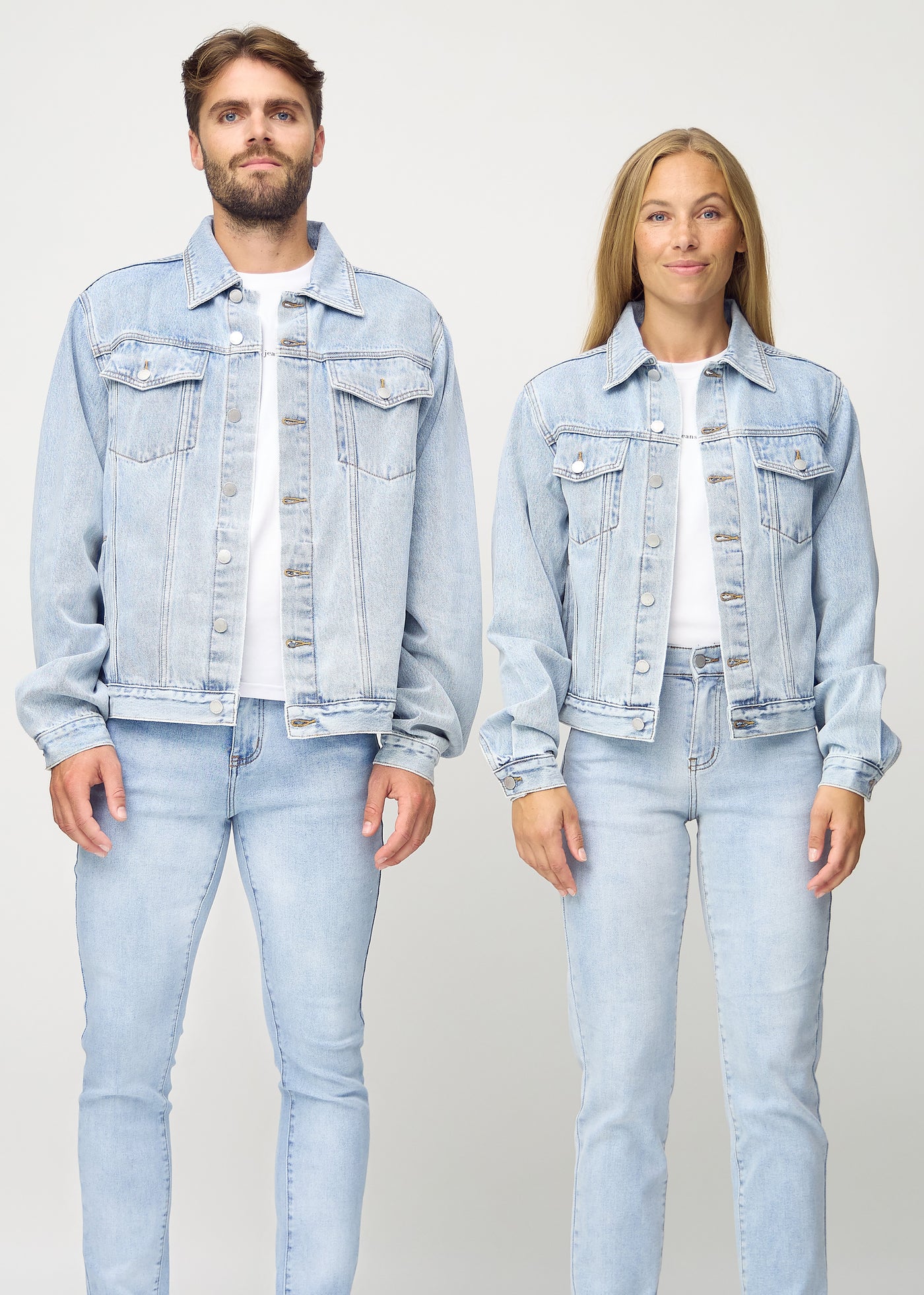 Unisex lyseblå denim jakke set forfra på herre- og damemodel, viser klassisk design med lige snit og knapper langs fronten. Jakken er i farven Waves.