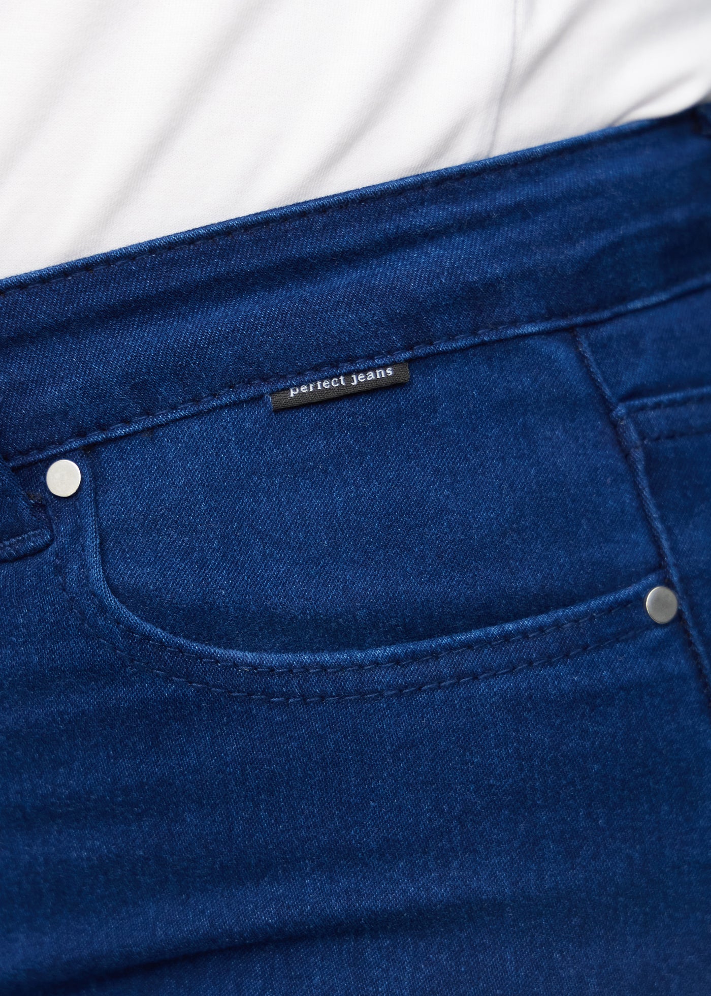 Forlommen på et par mørkeblå jeans, hvor man kan se logoet på en plus-size model.