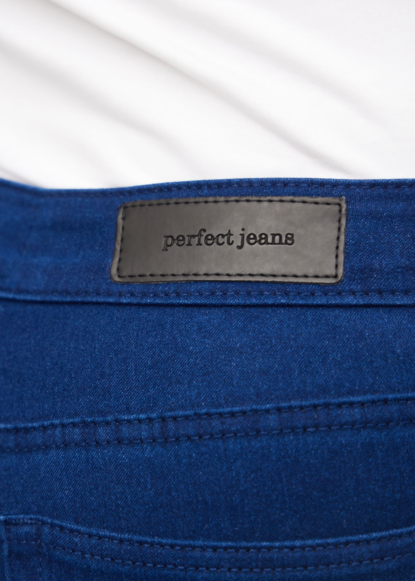 Baglommen på et par mørkeblå jeans, hvor man kan se logoet på en plus-size model.