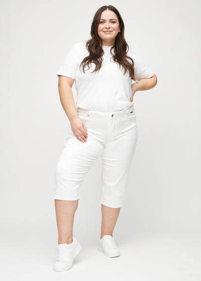 Plus-size model går ind i billedet, strækker i sine capris, viser dem frem ved at dreje rundt, og forlader derefter billedet.